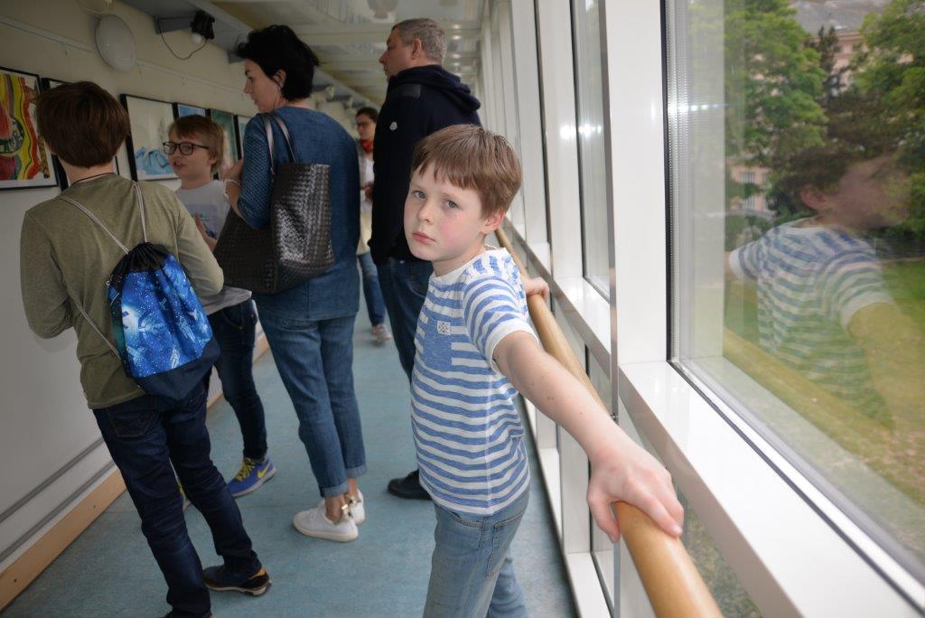 Ученики и их родители смотрят картины на выставке